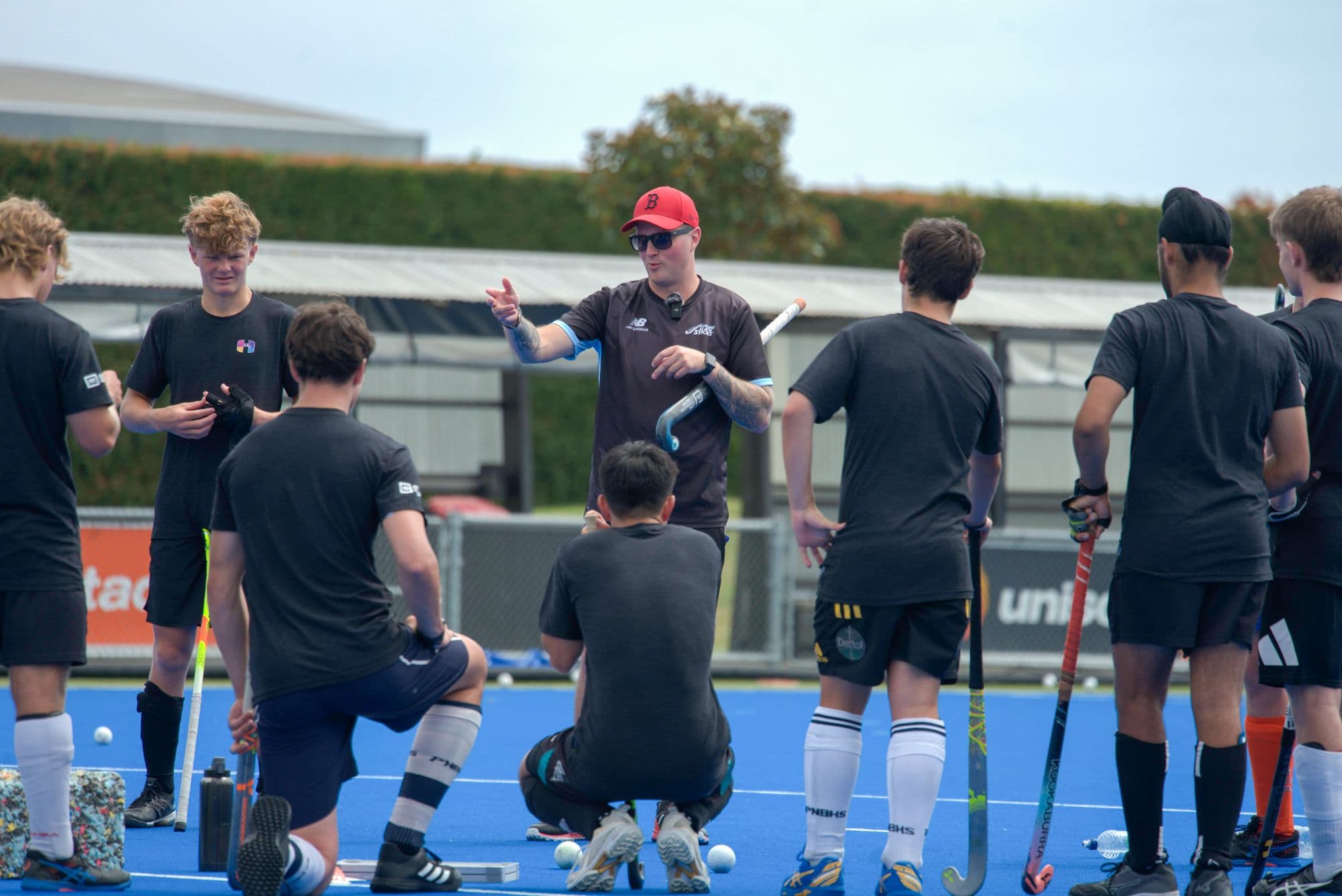 An Inside Hockey coach working with a group of Pathway players on blue turf.